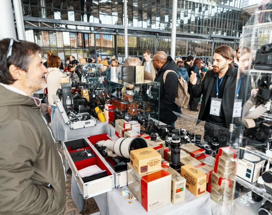 Marché de la photographie en plein air avec exposants, visiteurs et matériel photo vintage exposé sur les stands.