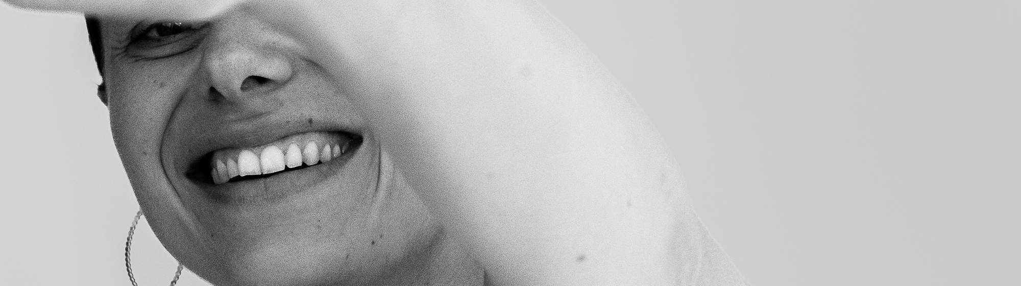 Portrait artistique en noir et blanc d’une femme souriante avec un tatouage en forme de cœur sur le bras
