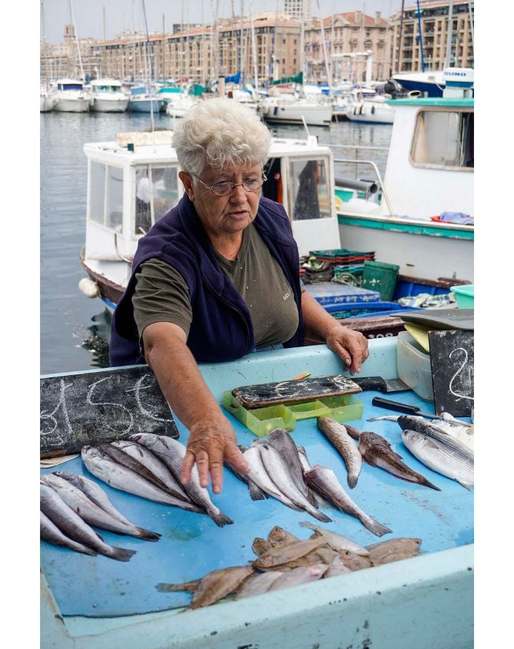 Femme âgée vend du poisson sur le marché