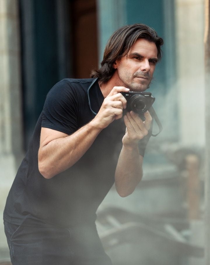Portrait de Christophe Brachet, photographe, tenant un appareil photo devant une vitre