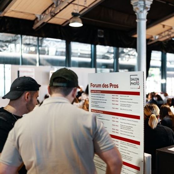 Deux visiteurs consultent le programme des conférences du Forum des Pros au Salon de la Photo.