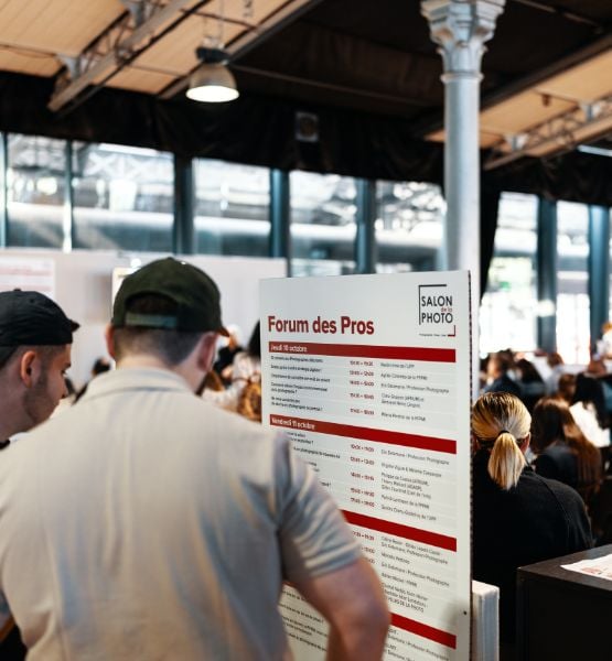 Personnes consultant le programme du Forum des Pros au Salon de la Photo, dans un espace lumineux et animé
