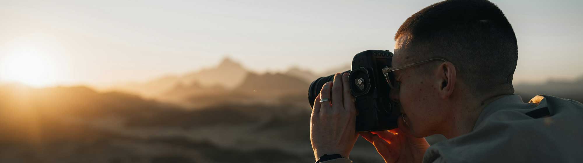 Un homme prend en photo des montagnes pendant un couché de soleil