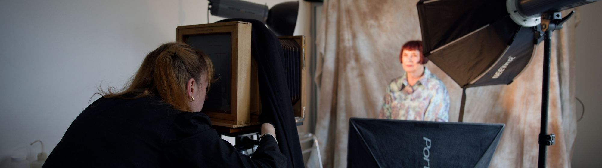Photographe prenant une photo en collodion humide dans un studio avec éclairage et fond.