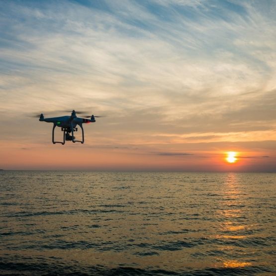 Drone volant au-dessus de la mer au coucher du soleil sous un ciel coloré
