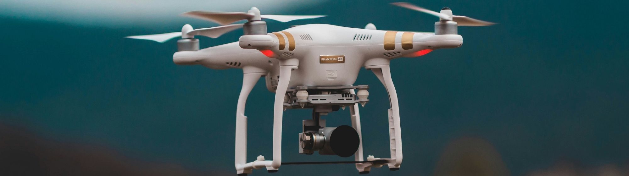 Drone quadricoptère blanc en vol au-dessus d’un paysage flou avec des montagnes en arrière-plan