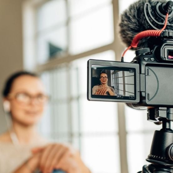 Femme filmée devant une caméra avec écran LCD visible