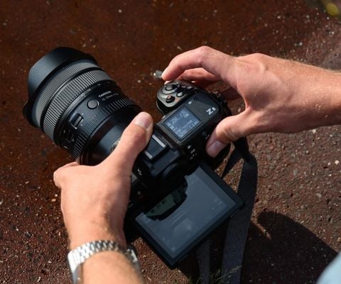 Photographe utilisant un appareil photo hybride avec objectif professionnel