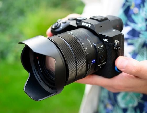 Appareil photo Sony RX10 tenu par une personne, prêt à photographier en extérieur