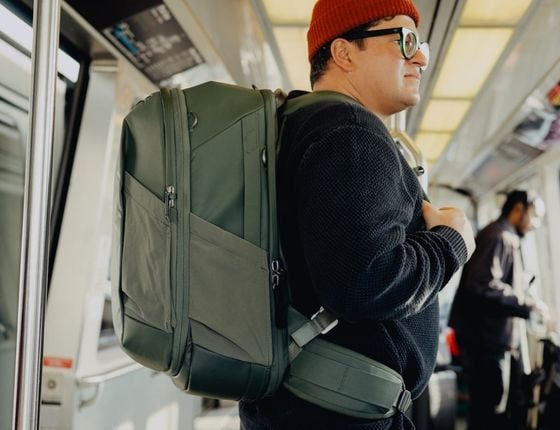 Homme portant un grand sac à dos de voyage vert dans les transports en commun