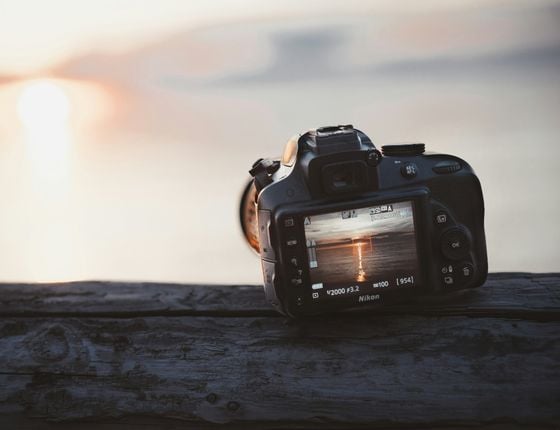 Appareil photo Nikon posé sur une surface avec vue du coucher de soleil sur l’écran