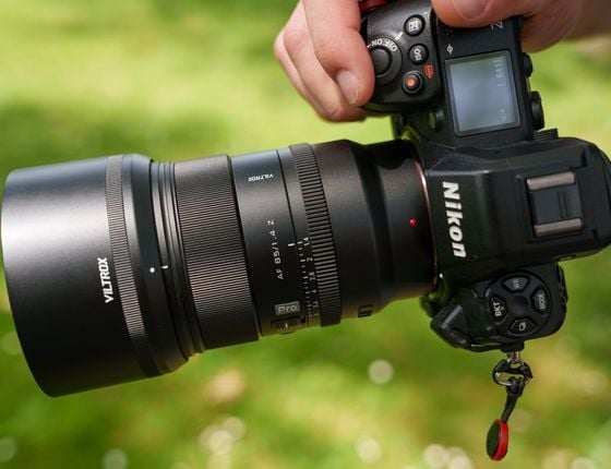 Photographe tenant un appareil Nikon avec objectif Viltrox 85mm