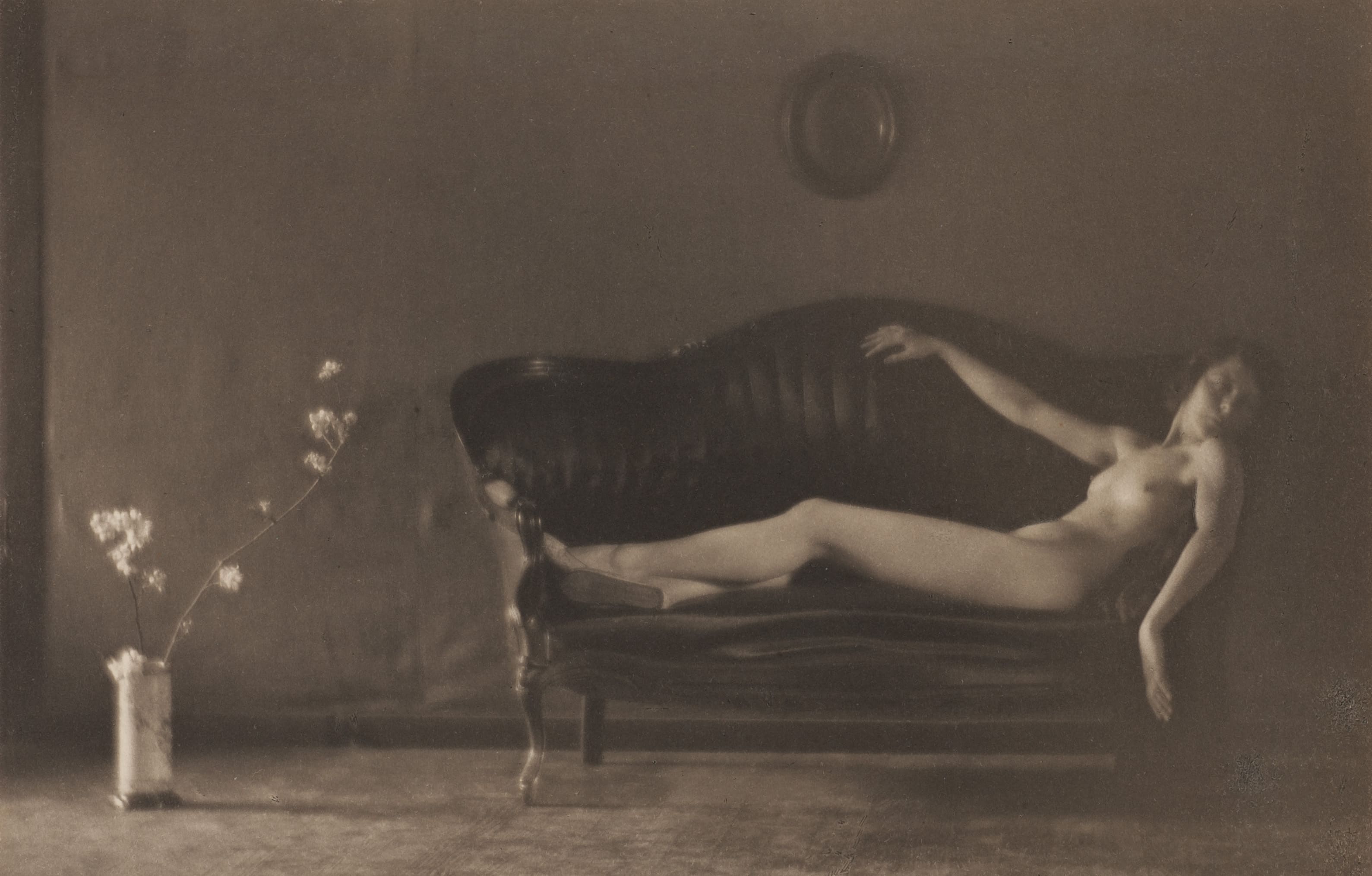 Photographie artistique en noir et blanc représentant un corps féminin allongé sur une méridienne dans une ambiance onirique et floue.