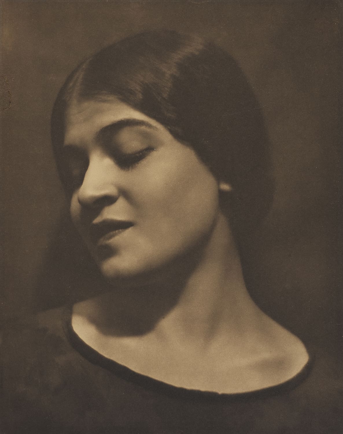 Portrait photographique en noir et blanc d’une femme au regard baissé, éclairage doux et atmosphère intimiste.