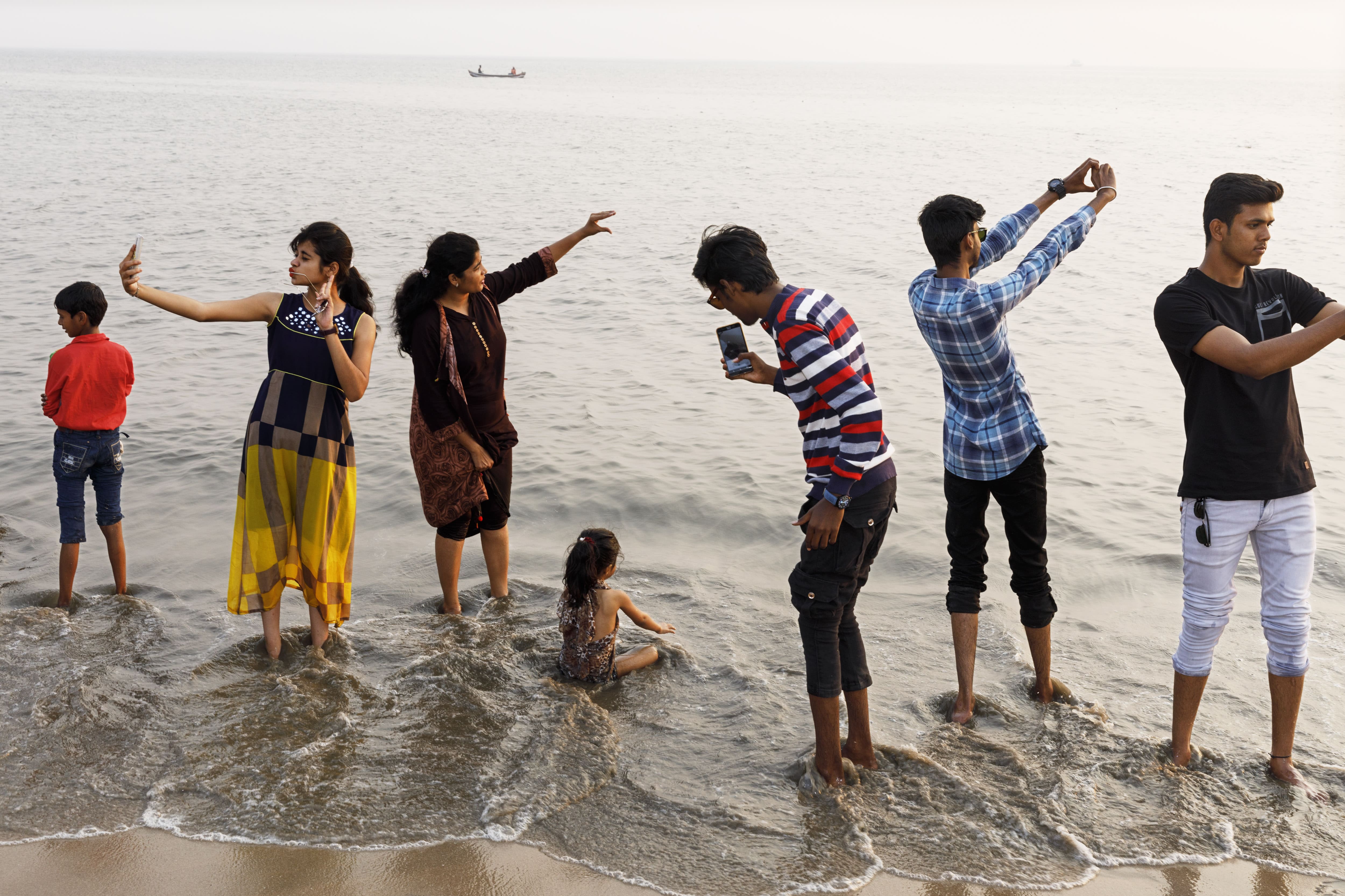 Groupe de personnes prenant des selfies au bord de la mer avec une vue en arrière-plan.