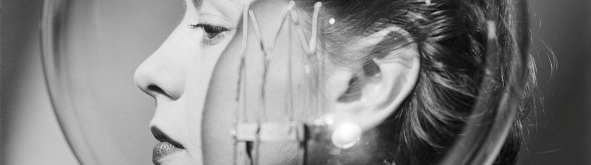 Portrait en noir et blanc d’une femme observée à travers une sphère en verre