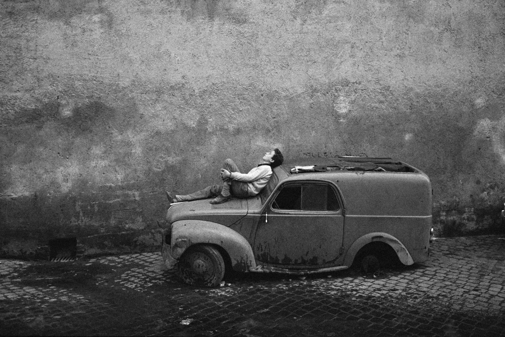 Photographie d'un homme allongé sur le capot d'une voiture