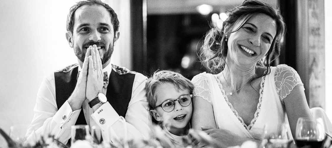 Photo en noir et blanc d'un couple à une table de mariage avec un enfant au milieu
